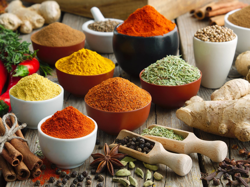 Des bols d'épices colorées : orange, jaune, rouge et verte avec du gingembre et de la cannelle.