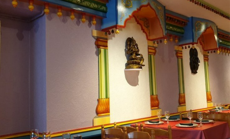Intérieur du RESTAURANT GANDHI avec des arcades décoratives peintes de couleurs vives, ornées de statues.
