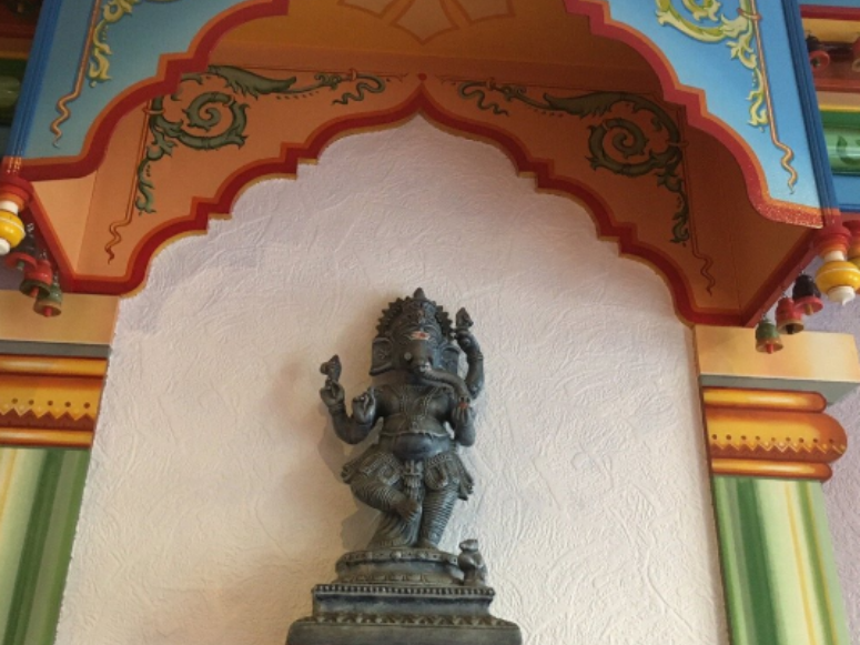 Statue de Ganesh sous une arche. Détails architecturaux colorés.