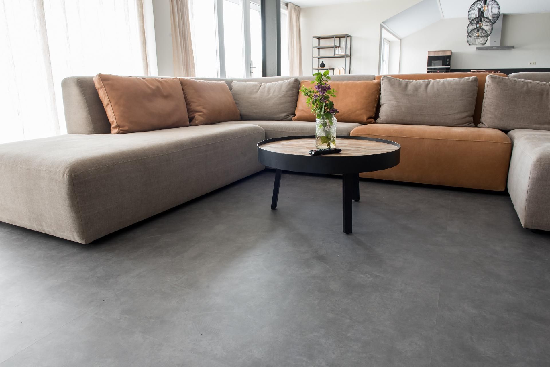 Modernes Wohnzimmer mit Ecksofa, Couchtisch und Blumen.