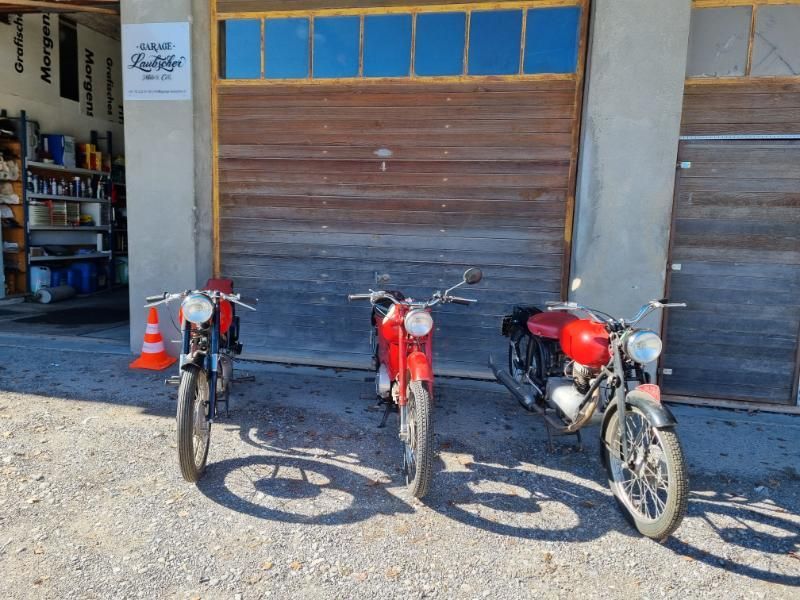 Drei Motorräder sind vor einem Garagentor geparkt