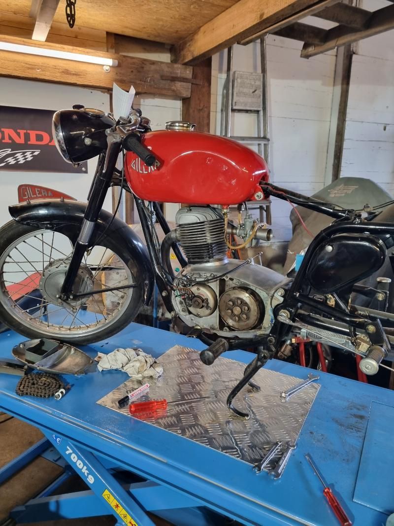 Ein rotes Motorrad steht auf einem blauen Tisch in einer Garage