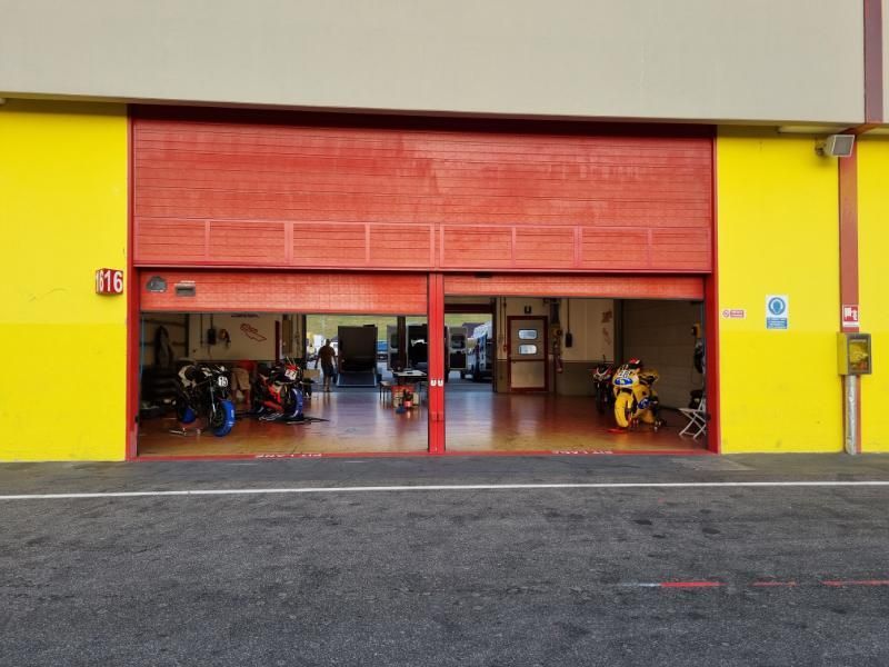 Ein rotes Garagentor zu einer Motorrad-Reparaturwerkstatt steht offen