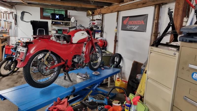 Ein rotes Motorrad steht auf einem blauen Tisch in einer Garage.
