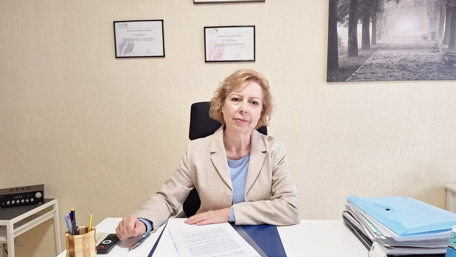 Una mujer está sentada en un escritorio en una oficina sosteniendo un bolígrafo.