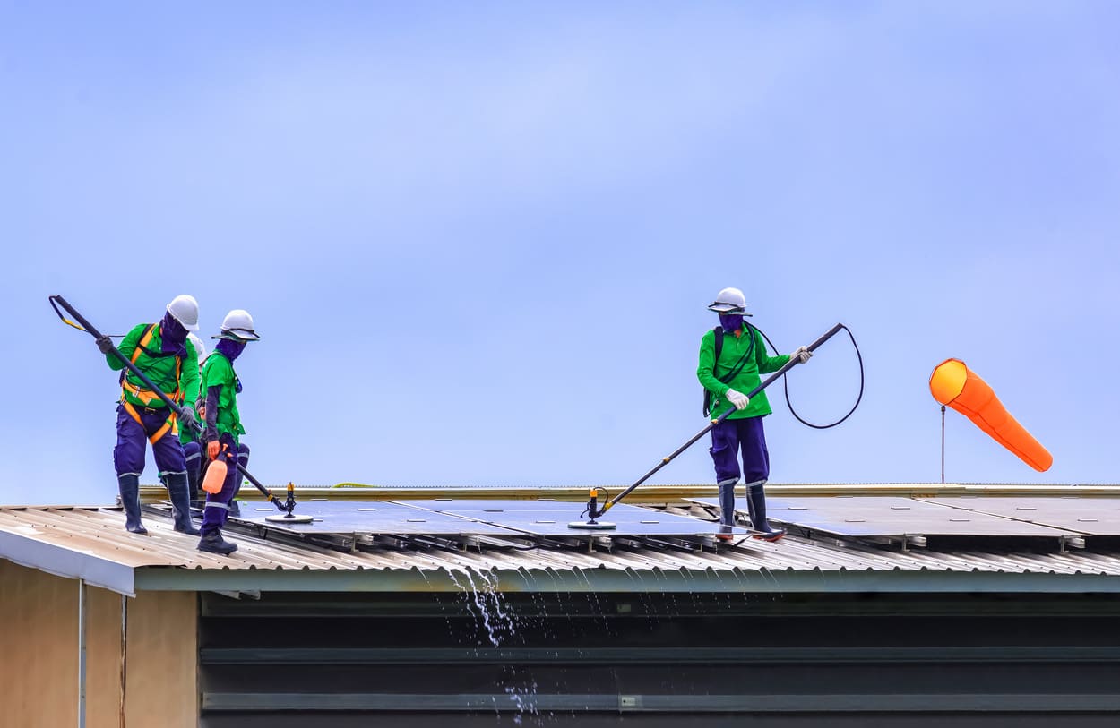 Trois personnes qui nettoient un panneau solaire