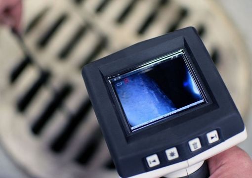 Person reinigt ein Rohr auf einer Straße