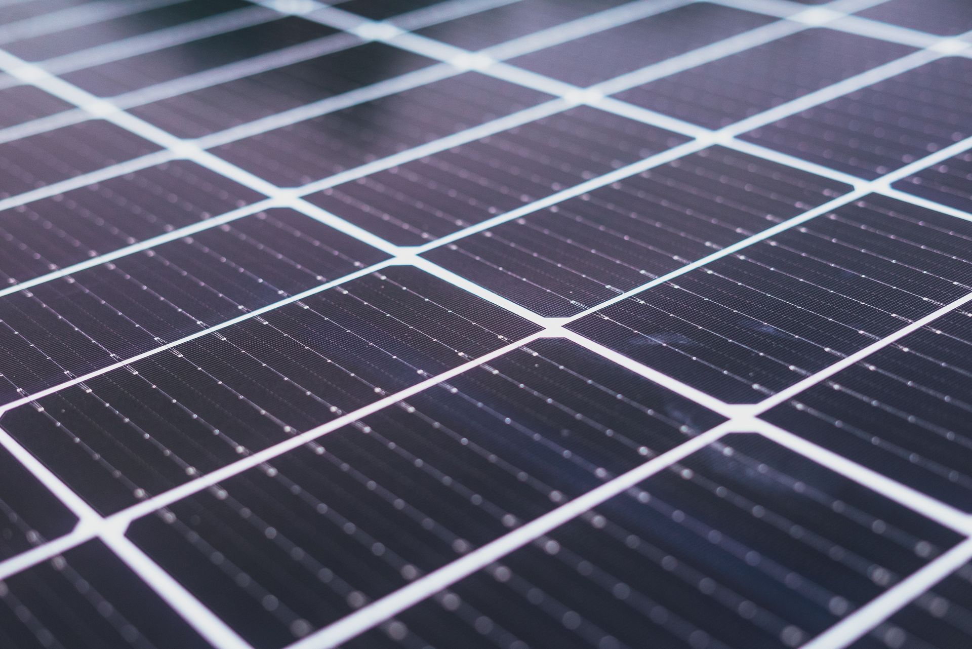 Primer plano de paneles solares con células fotovoltaicas de color azul oscuro y líneas de rejilla blancas.