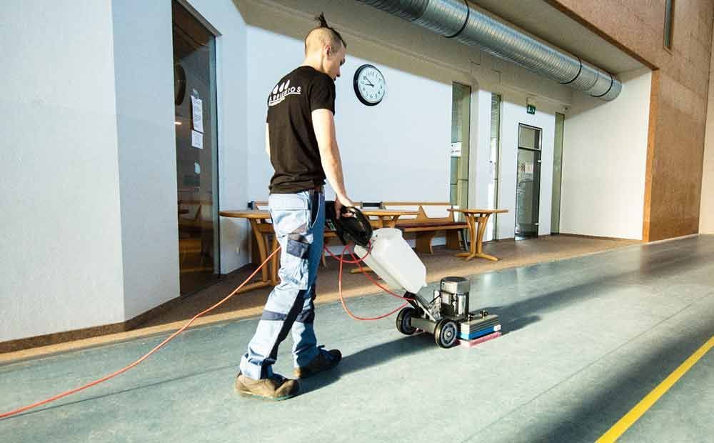 Ein Mann reinigt den Boden mit einer Maschine.