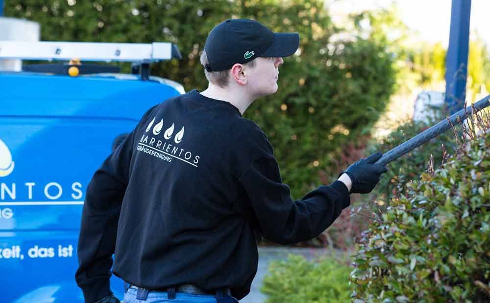 Ein Mann steht mit einem Schlauch in der Hand vor einem blauen Lieferwagen.