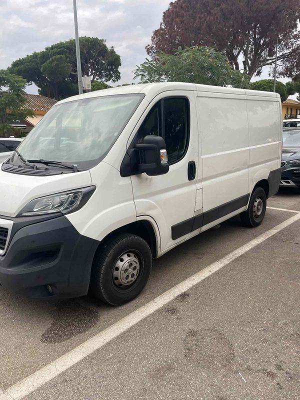 Furgoneta de carga blanca estacionada sobre una superficie pavimentada.