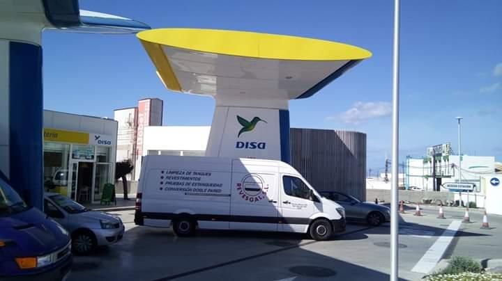 Tanque cilíndrico de metal brillante con brida atornillada contra un cielo nublado.