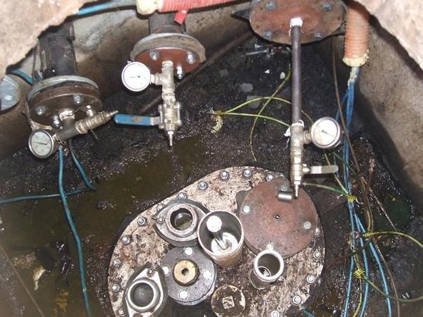 Vista aérea del área de acceso abierto de un tanque industrial; incluye medidores, tuberías y líquido residual.