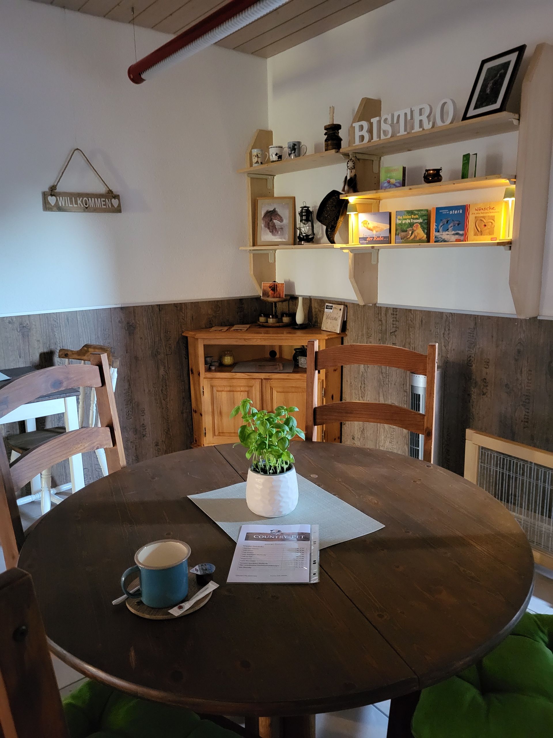 Ein Tisch mit einer Tasse Kaffee darauf in einem Raum mit einem Schild an der Wand, auf dem „Bistro“ steht.