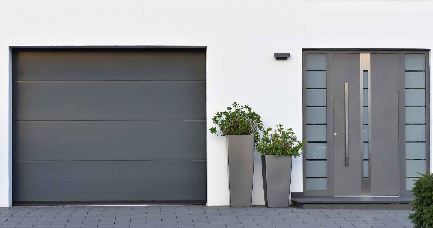 Porte de garage moderne à côté de la porte d'entrée d'une habitation