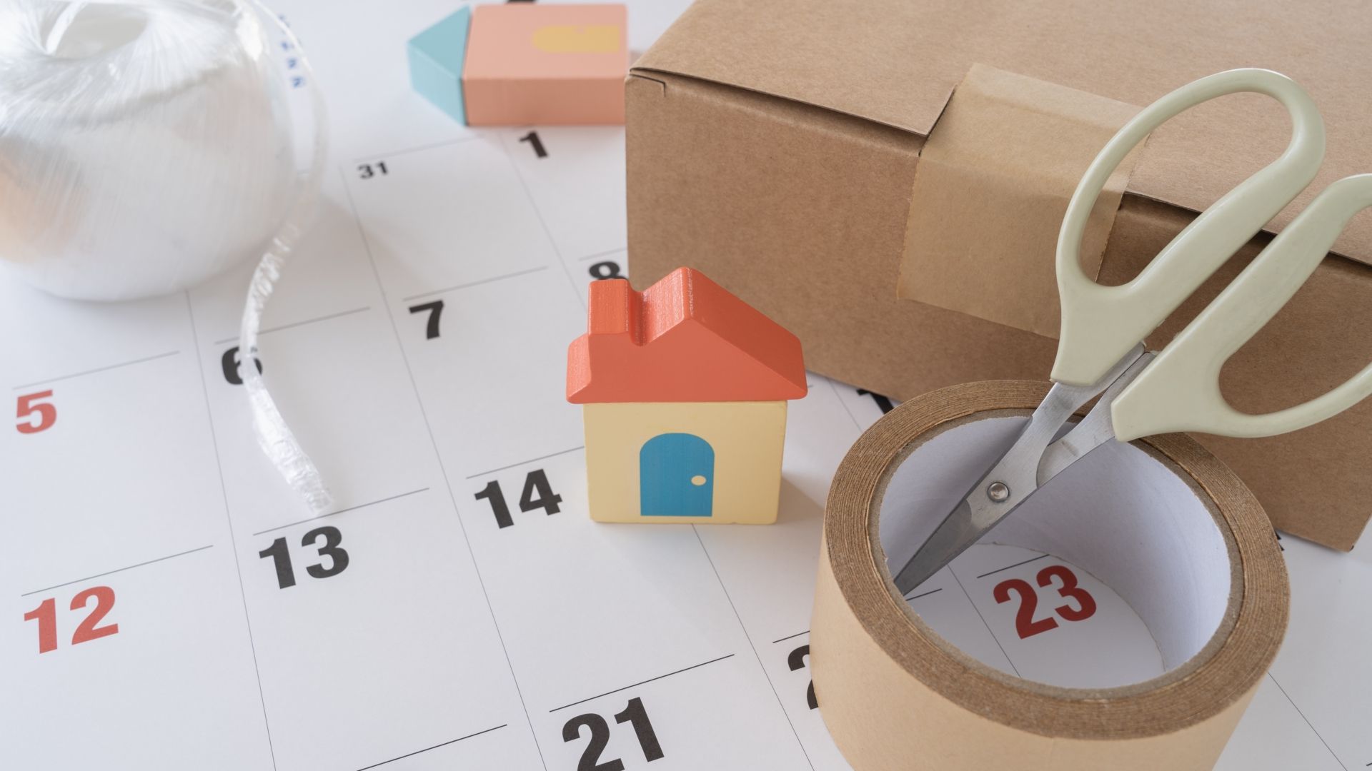 Ein Kalender mit einer Schere, die ein markiertes Datum ausschneidet, daneben eine Klebebandrolle und ein kleines Haussymbol.