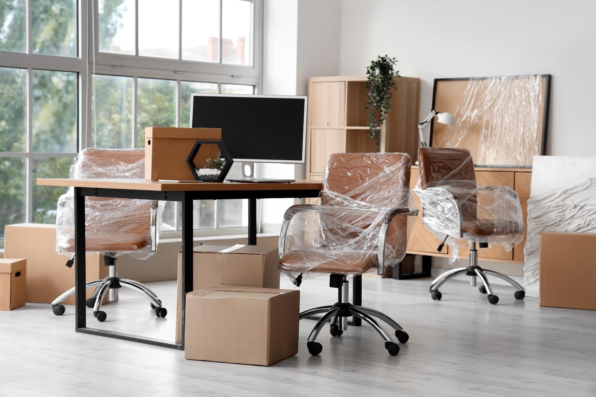 Leeres Büro mit Schreibtischen, verpackten Stühlen, Umzugskartons und einem im Gange befindlichen Umzugsaufbau.