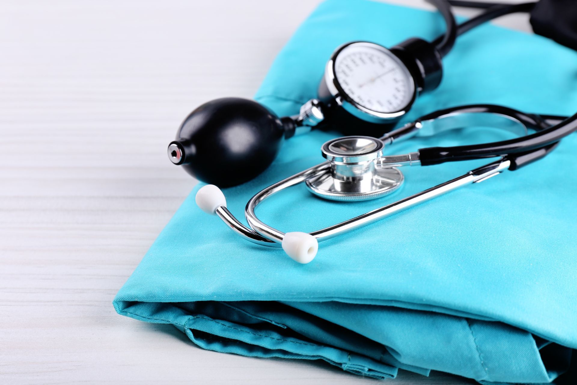 Stéthoscope et brassard de tensiomètre sur une blouse médicale bleue.