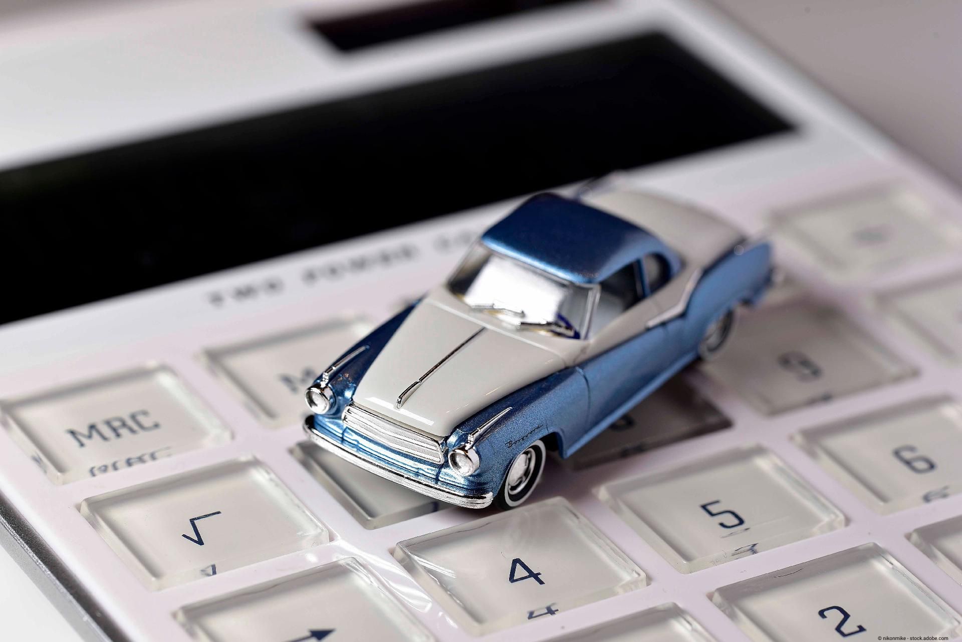 Modellauto in Hellblau und Weiß steht auf einer weißen Taschenrechner-Tastatur