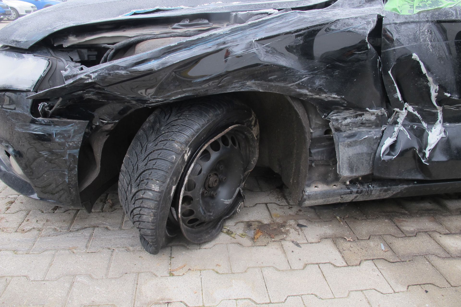 Vorderer Bereich eines stark beschädigten Autos mit deformiertem Reifen und eingedrücktem Kotflügel