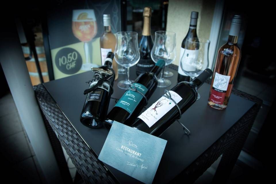 Bouteilles de vin et de spiritueux exposées sur une table noire dans un intérieur faiblement éclairé