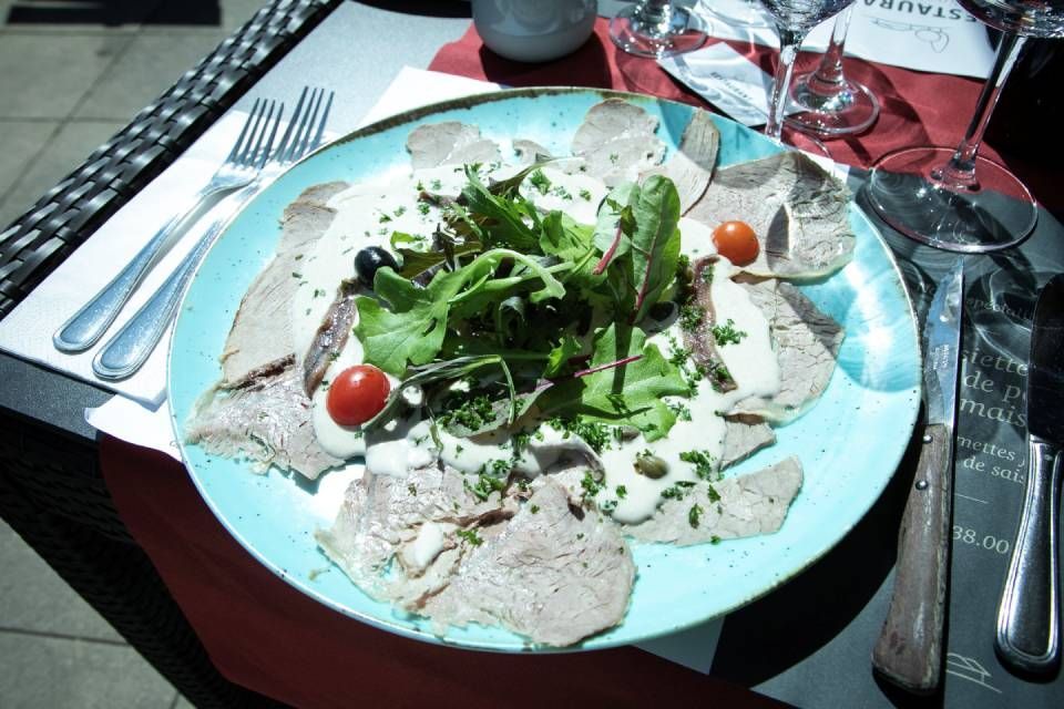 Assiette de salade de viande tranchée avec de la verdure et des tomates cerises sur une table à manger