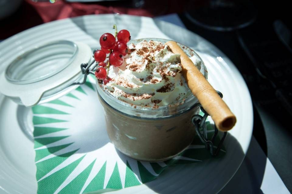 Café fouetté aux groseilles rouges et gaufrette sur une assiette blanche au soleil