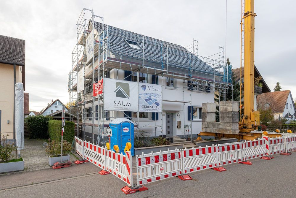 Ein im Bau befindliches Gebäude mit Gerüst und einem Kran davor.