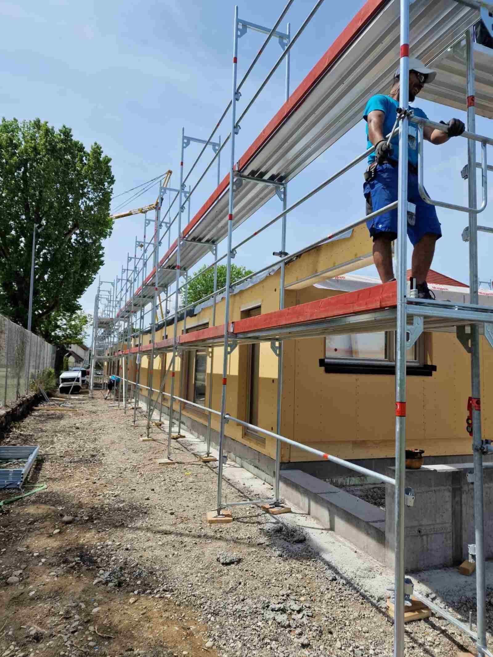 Ein Mann steht auf einem Gerüst auf einem Gebäude.
