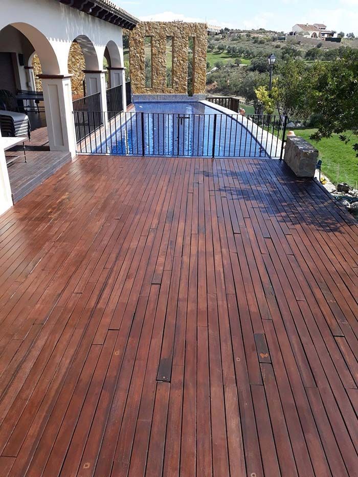 Terraza de madera junto a una piscina con una vista panorámica al aire libre.