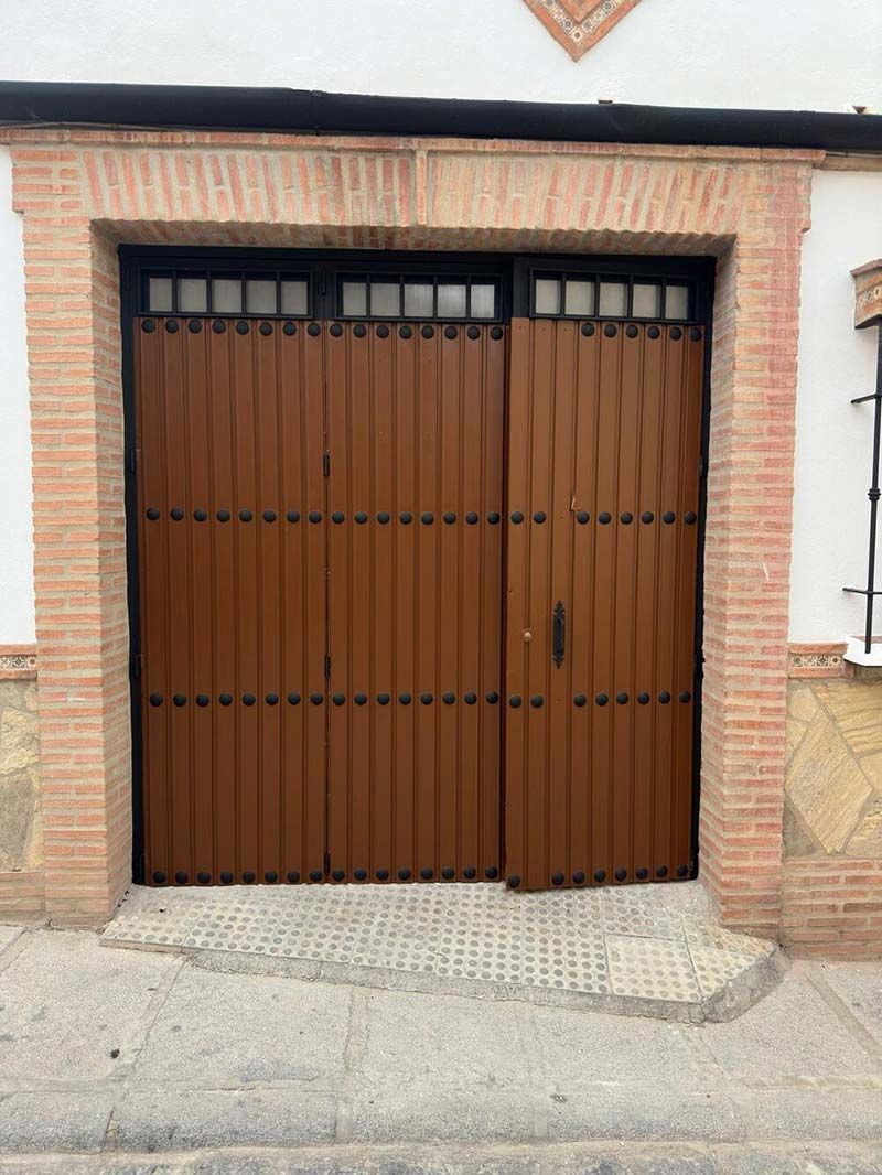 Puerta de garaje de metal marrón con moldura de ladrillo.