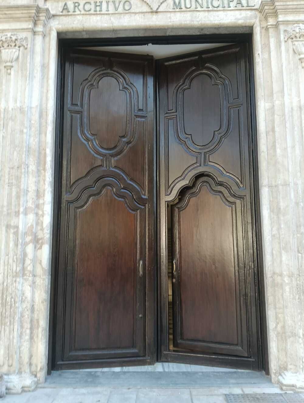 Puertas dobles de madera con tallas ornamentales, etiquetadas 