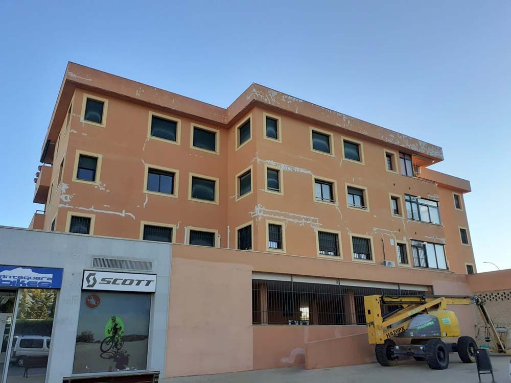 Edificio naranja con ventanas, tienda de bicicletas Scott y maquinaria de construcción.