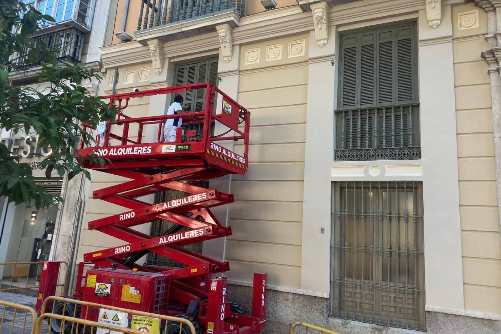 Obrero en un rascacielos, con vistas a la ciudad. Lleva arnés de seguridad y casco.