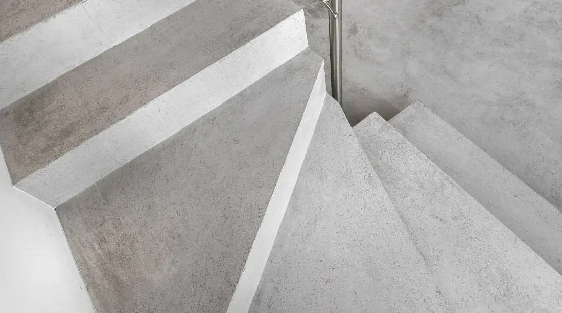 Un primer plano de una escalera de caracol de hormigón con barandilla de metal.
