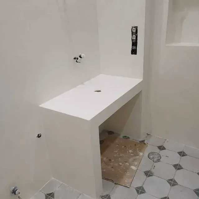 Un baño con lavabo blanco y suelo de baldosas.