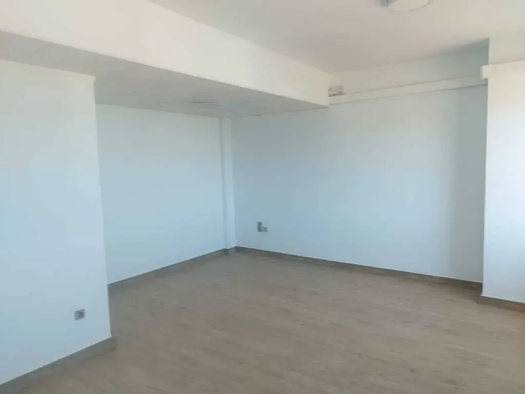 Una habitación vacía con paredes blancas y suelo de madera.
