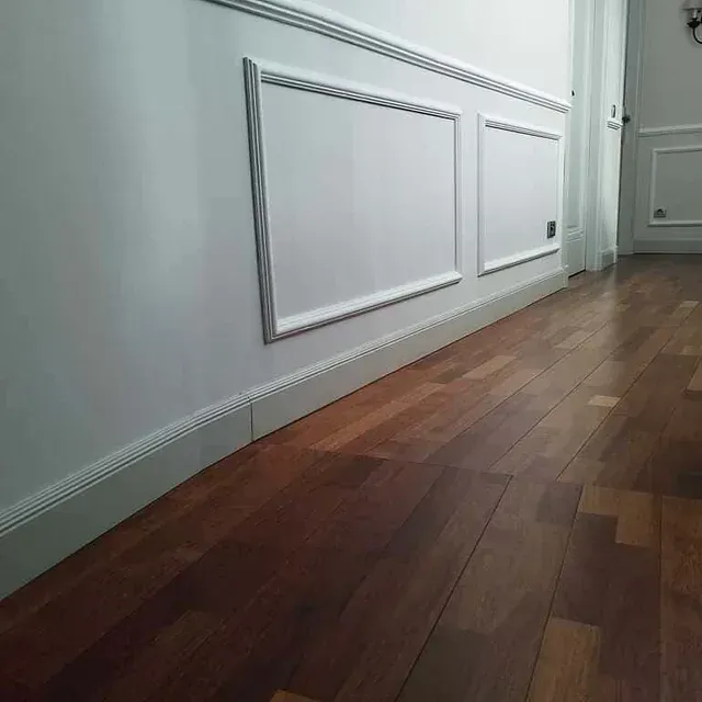 Un pasillo con pisos de madera y paredes blancas.