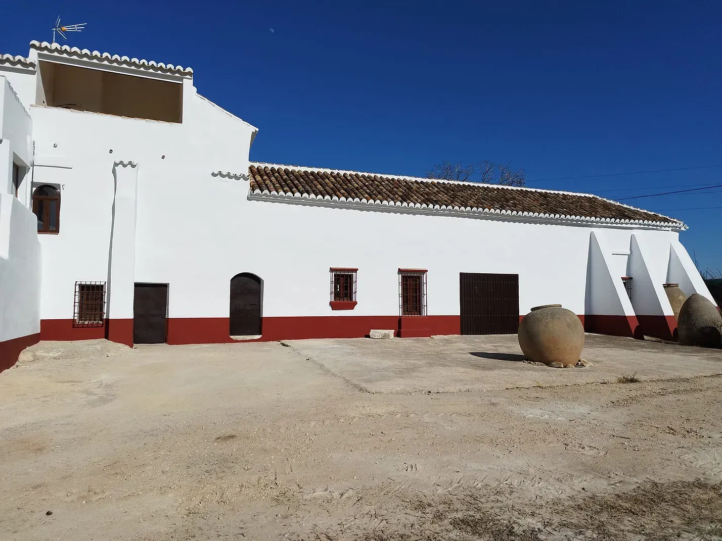 Un edificio blanco con detalles rojos y un cielo azul al fondo.