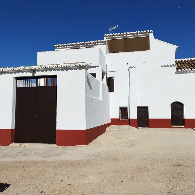 Un edificio blanco con detalles rojos y una puerta negra.