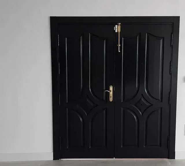Un par de puertas negras con manijas doradas en una pared blanca.