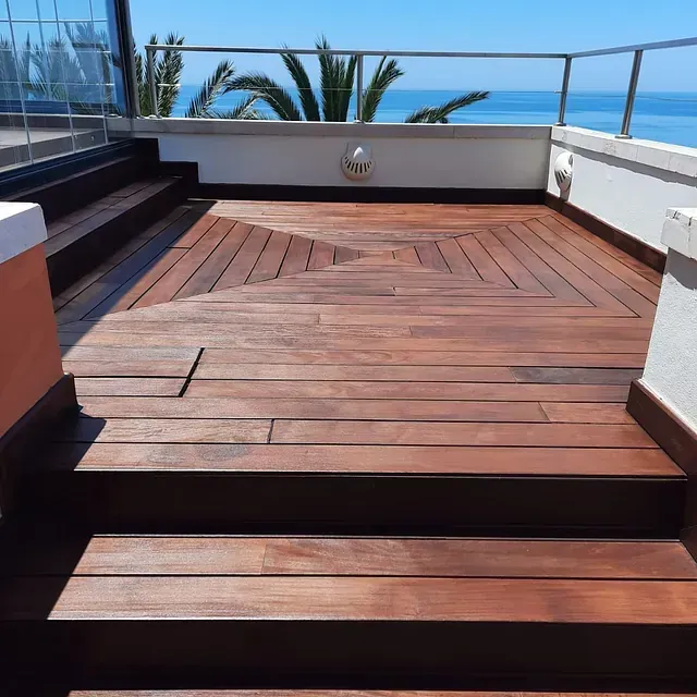 Una terraza de madera con escaleras que conducen al océano.