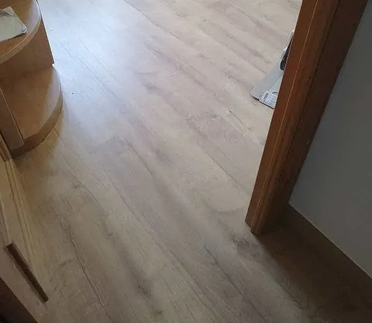 Un piso de madera en una habitación al lado de una puerta.