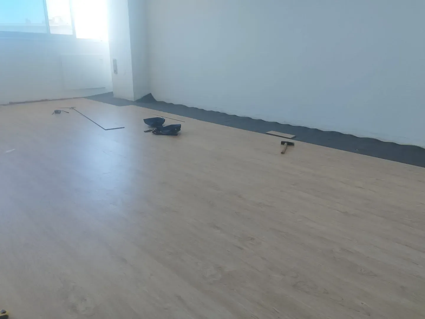 Una habitación con suelo de madera y un martillo en el suelo.