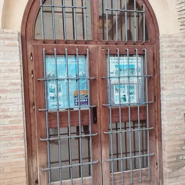 Un edificio de ladrillo con una puerta de madera con rejas.
