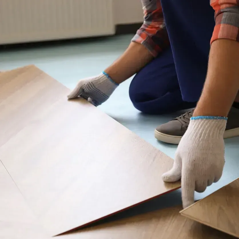 Persona con guantes instalando suelo, arrodillada en el interior.