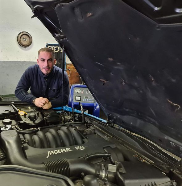 Getriebespülung Ein Mann sitzt unter der Motorhaube eines Jaguar V8