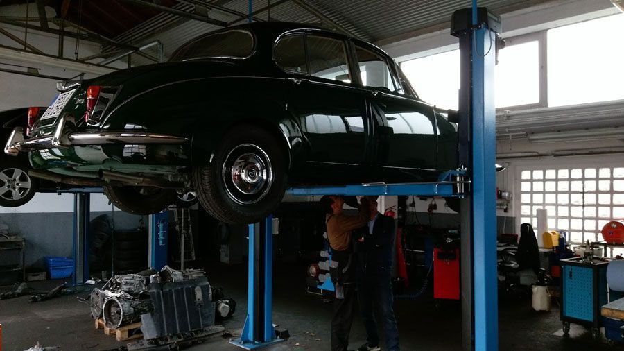 Ein grünes Auto steht auf einer Hebebühne in einer Garage.