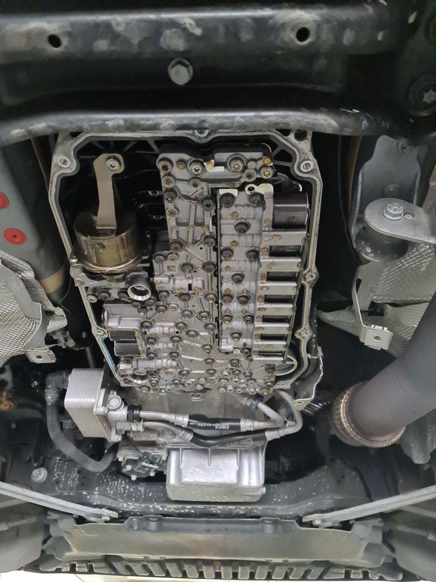 Eine Nahaufnahme der Unterseite eines Autos mit ausgebautem Getriebe.