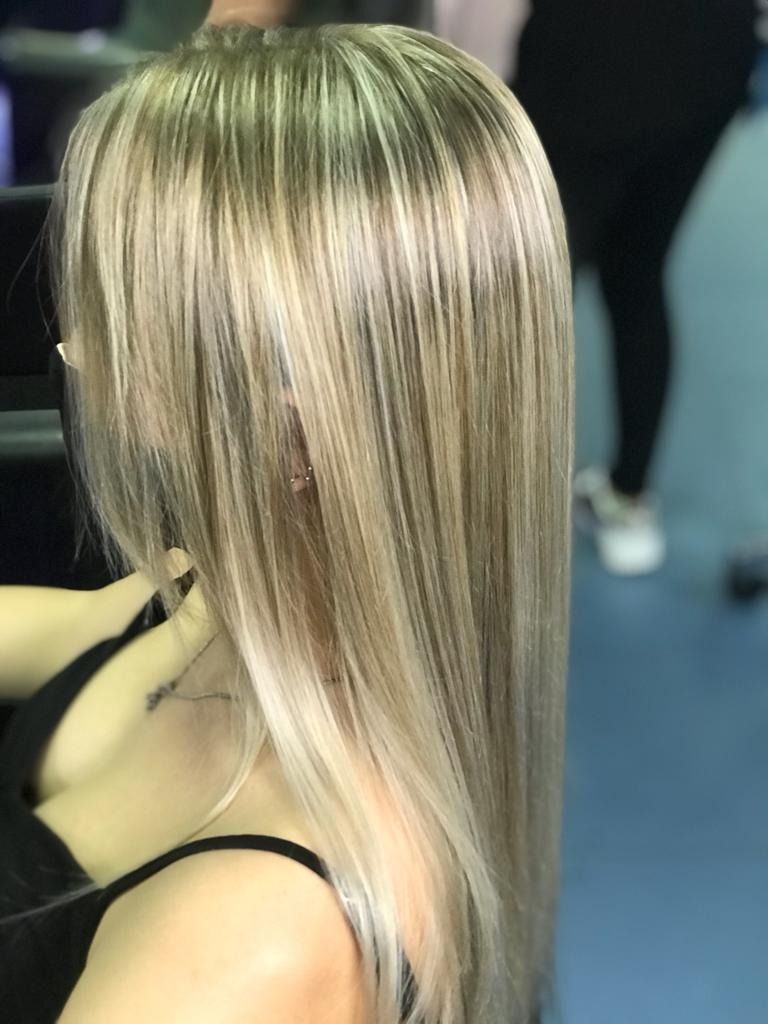 Mujer con cabello rubio largo, liso y con reflejos.